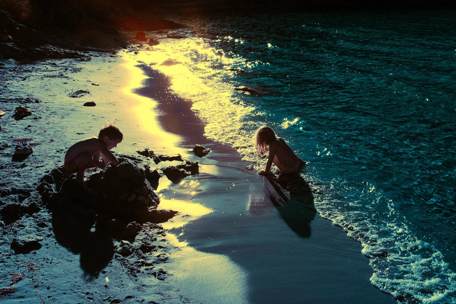 Deux personnes dans l&rsquo;eau entre des rochers sombres.