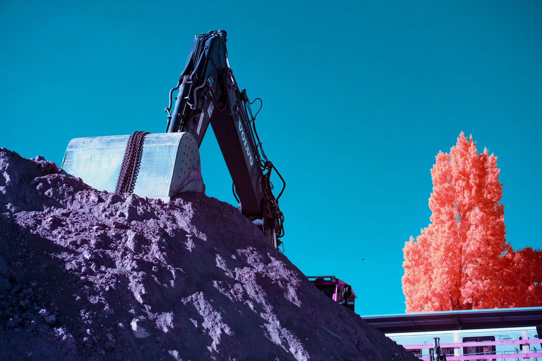 Bagger vor einer Landschaft in Infrarotfarben.