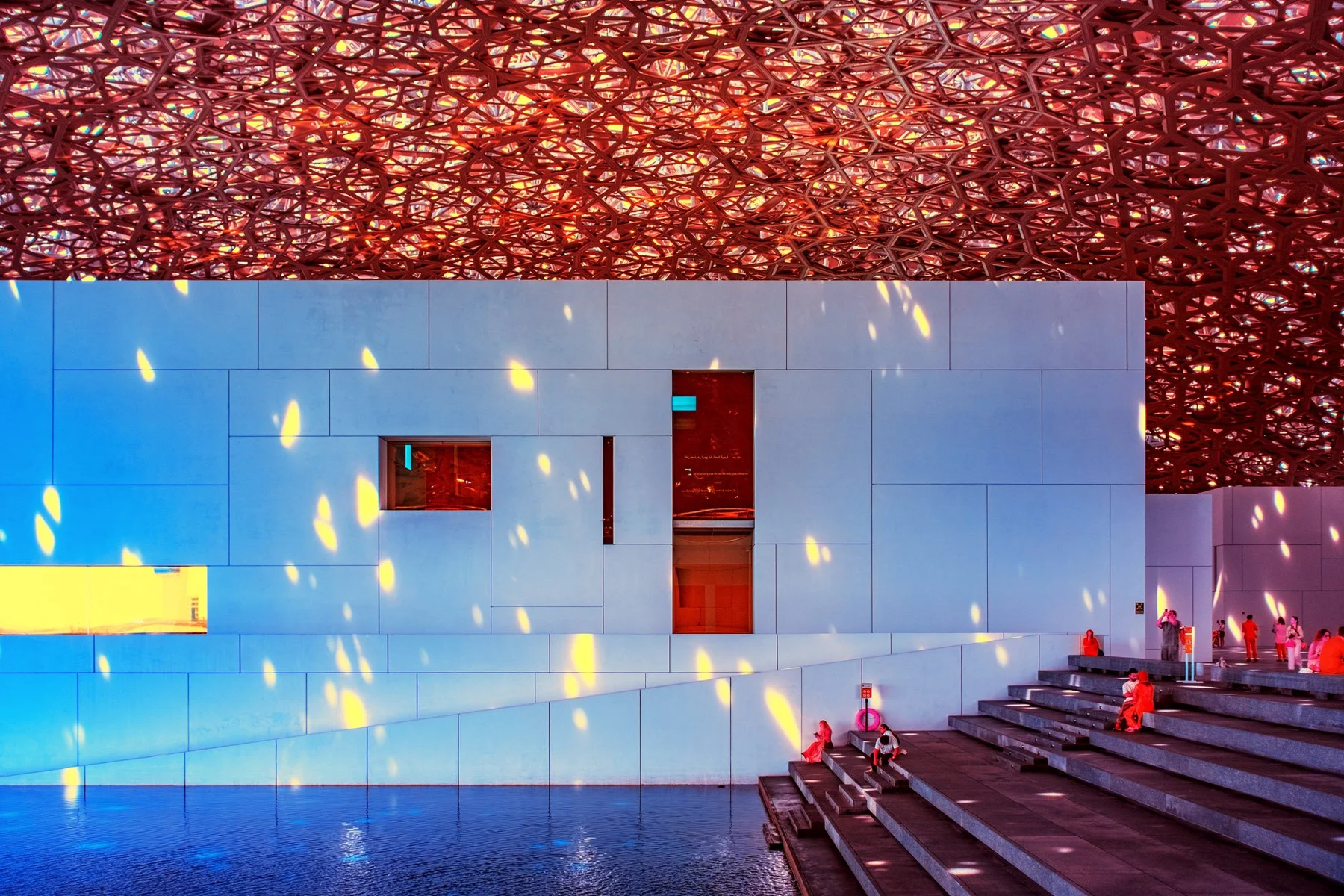 Lichtflecken auf einer wei&szlig;en Museumsfassade unter geometrischem Dach.