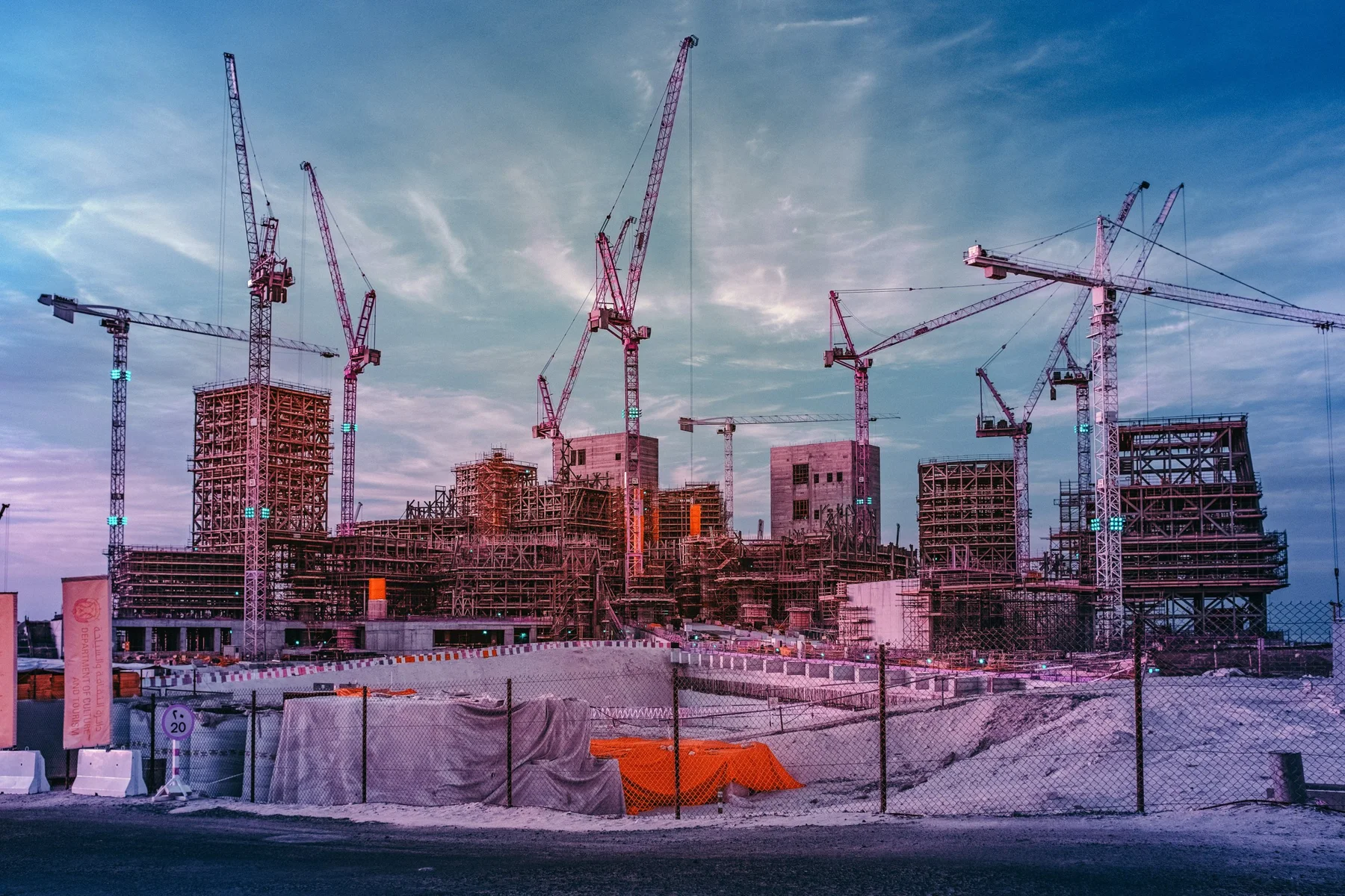 Bauplatz mit mehreren Kr&auml;nen und Stahlger&uuml;sten bei Sonnenuntergang, Baustelle im Bau.