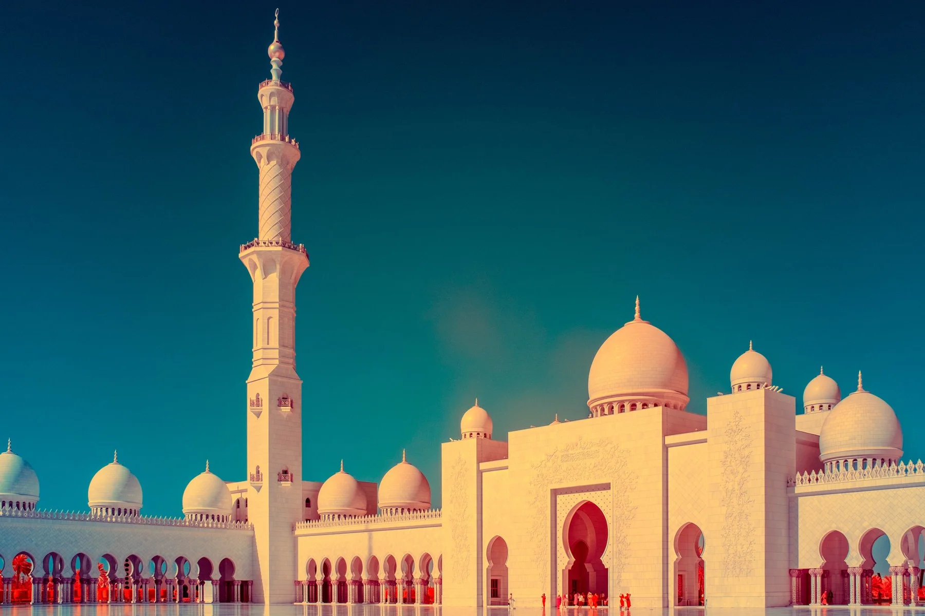 Moscheefassade mit Minarett und mehreren Kuppeln.